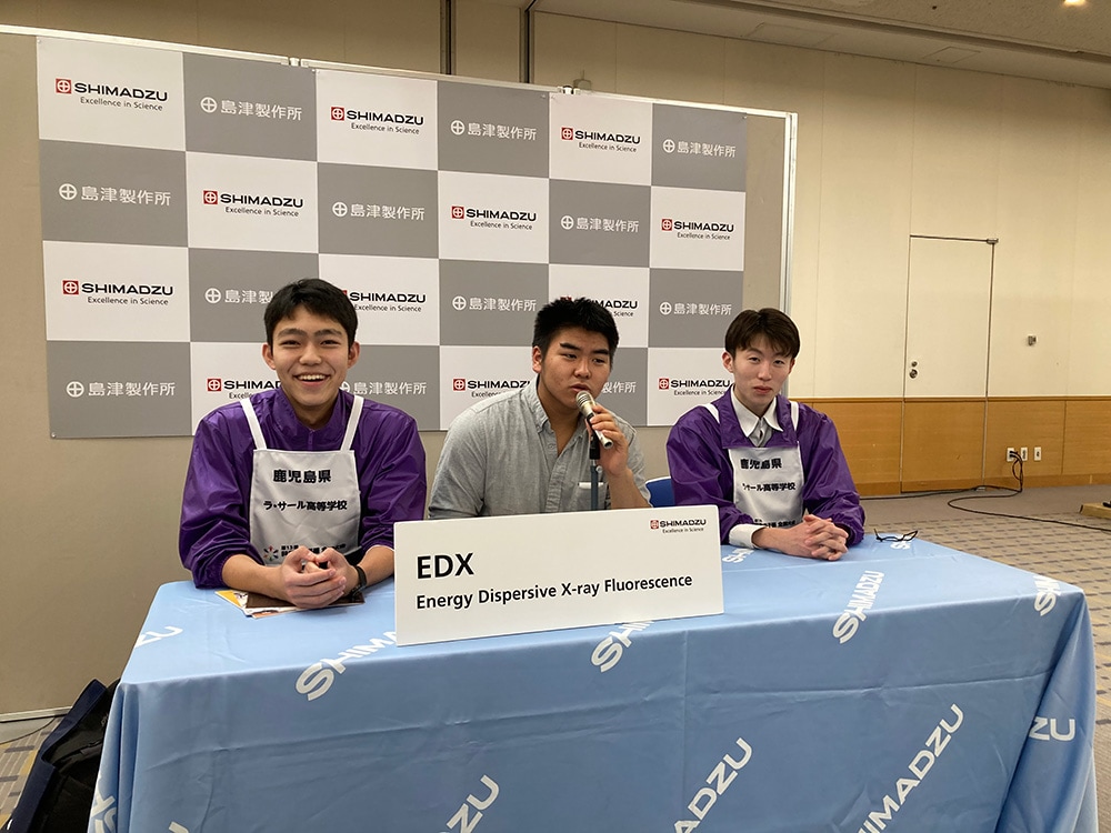 参赛者在看起来像新闻发布会场地的拍照点假扮主持人