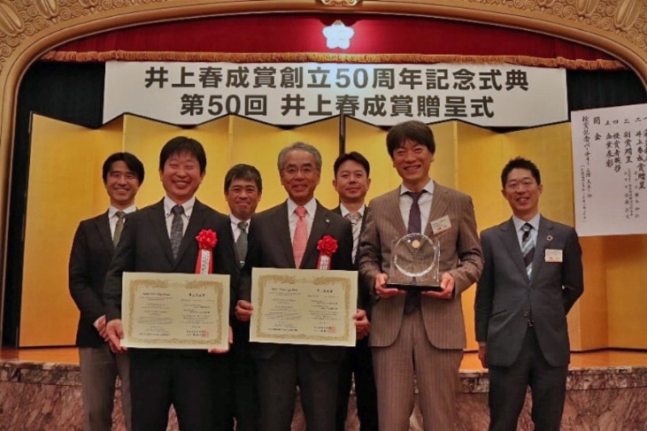岛津所社长山本靖则(前排中央)手持获奖证书,九州大学生物调节医学研究所马场健史教授(前排左侧)
